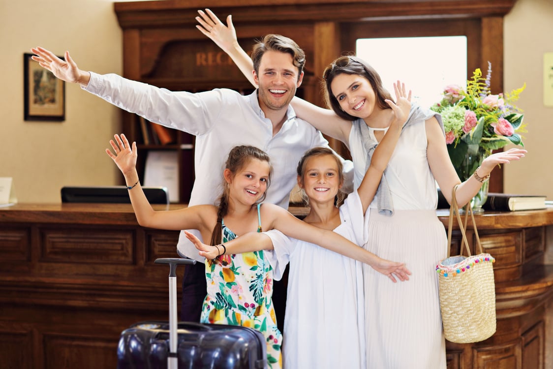 Happy Family Checking in Hotel at Reception Desk